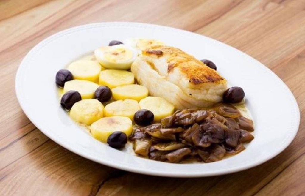 prato com bacalhau, cebola caramelizada, batatas, azeitonas pretas e ovos cozidos