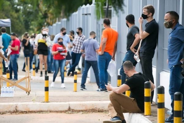 Pessoas em fila em frente a portão