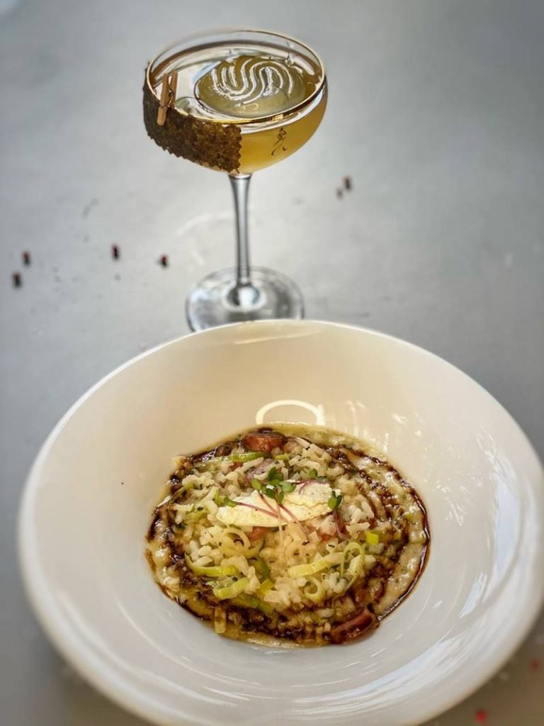 Prato com risoto e drinque ao fundo