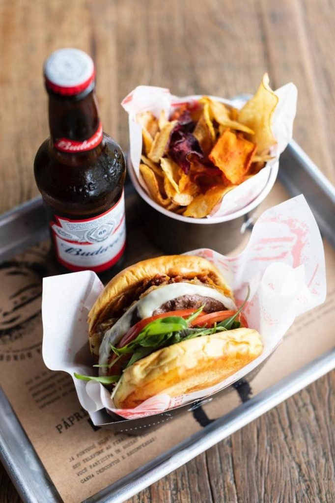 Hambúrguer, porção de raízes chips e cerveja em uma bandeja