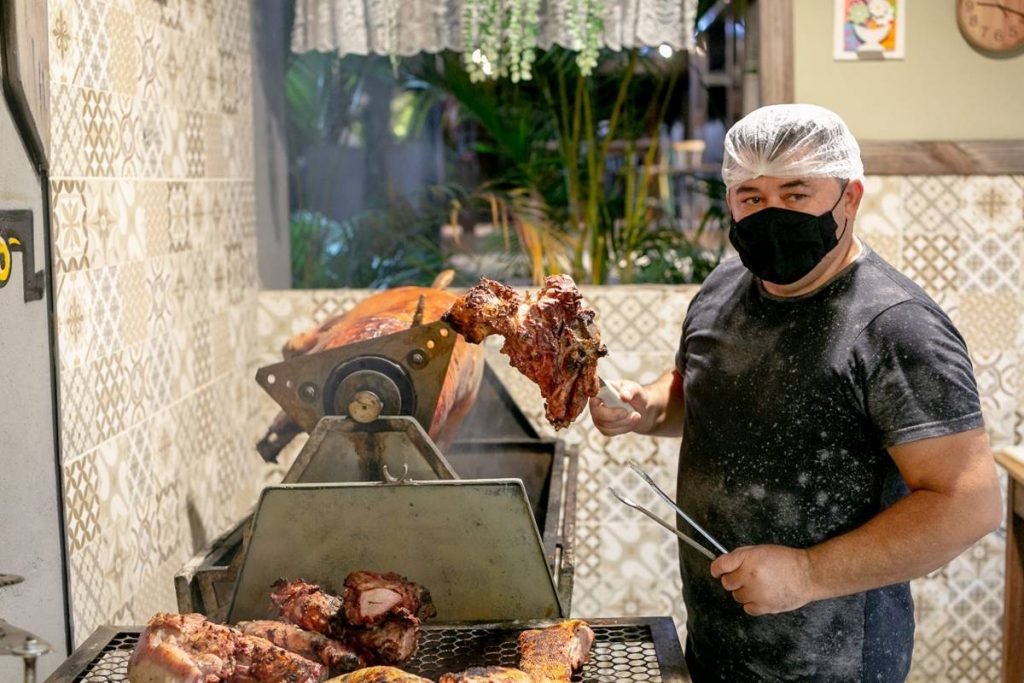 Churrasqueiro segura pedaço de carne assada