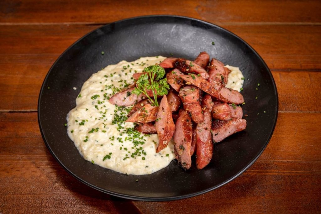 Prato preto com linguiça e creme de milho