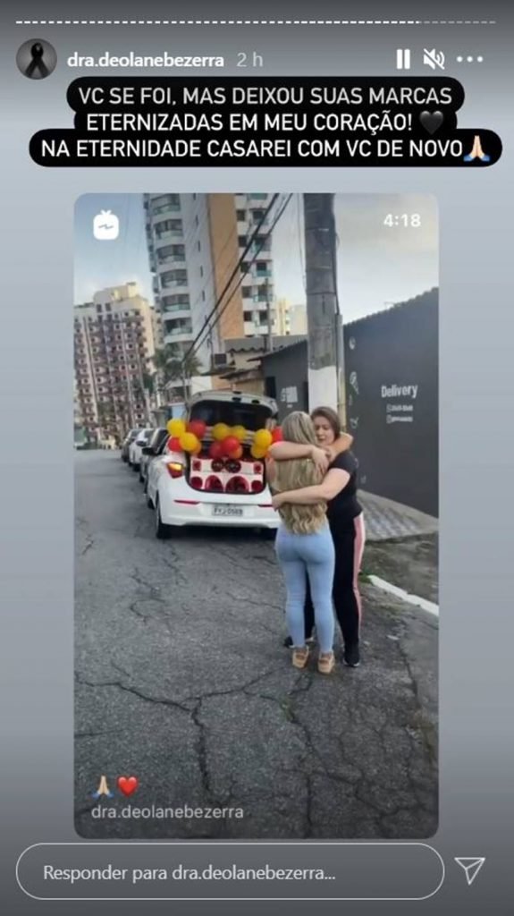 Duas mulheres se abraçam e choram emocionadas com carro de som ao fundo