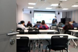 Fotografia de sala de aula com mesas e alunos