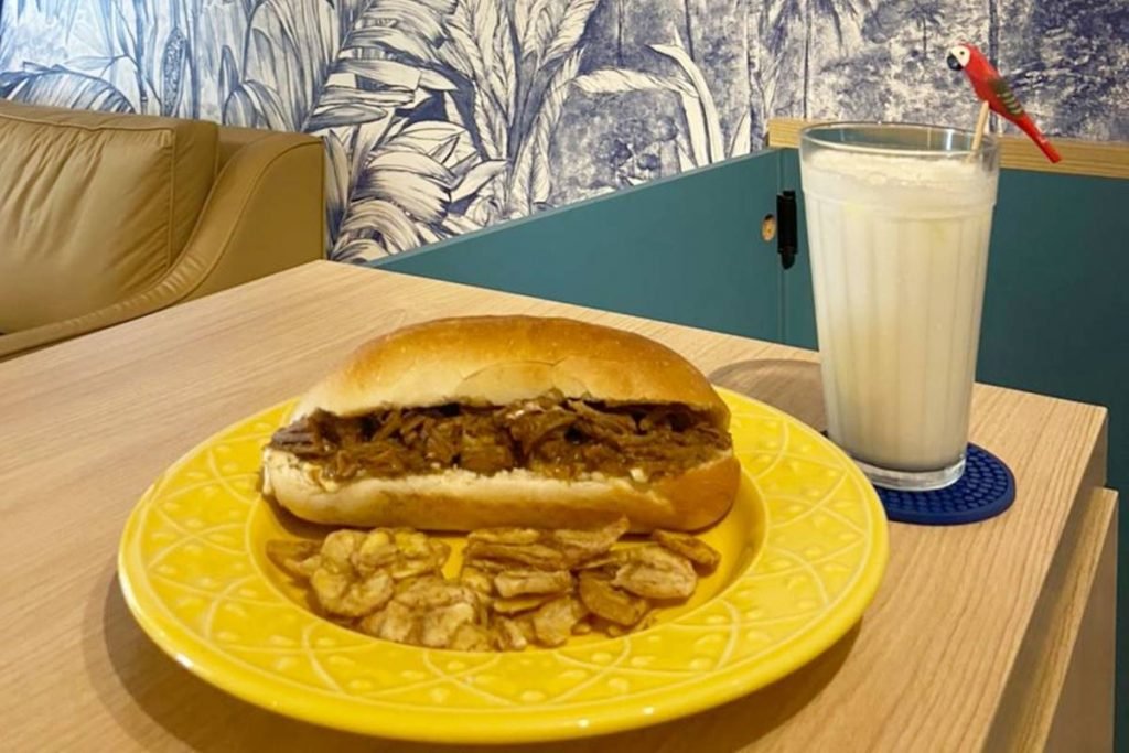 Prato com pão recheado com carne desfiada e copo de limonada de coco ao lado