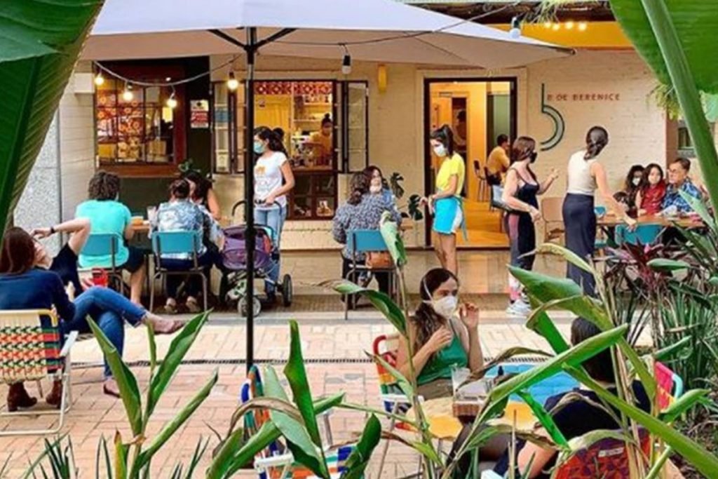 Espaço aberto com mesas e pessoas sentadas