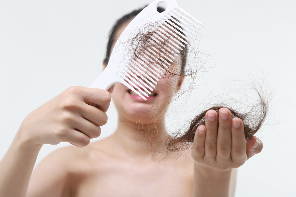 Mão de menina segurando o secador de cabelo.