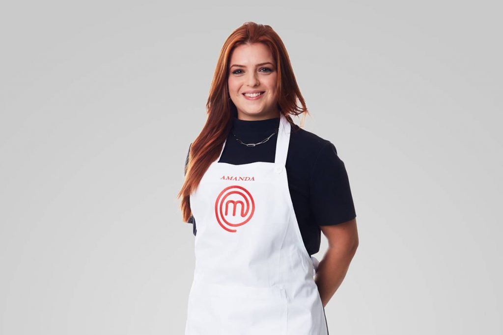 Mulher posa com avental do masterchef e sorri