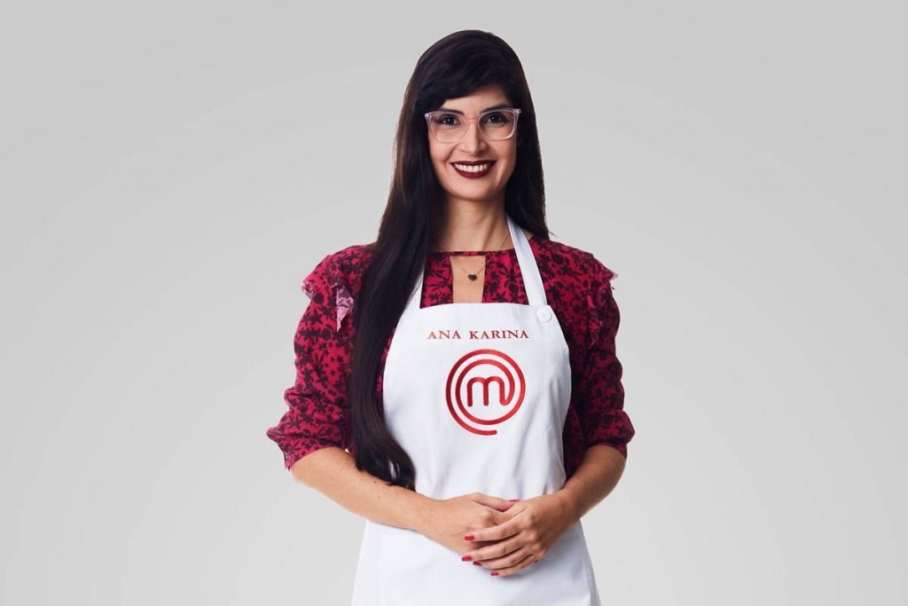 Mulher posa com avental do masterchef e sorri