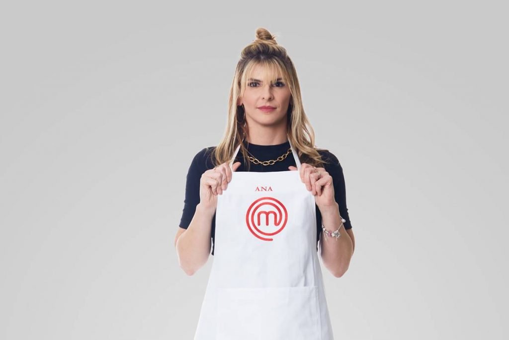 Mulher sorri segurando avental do masterchef