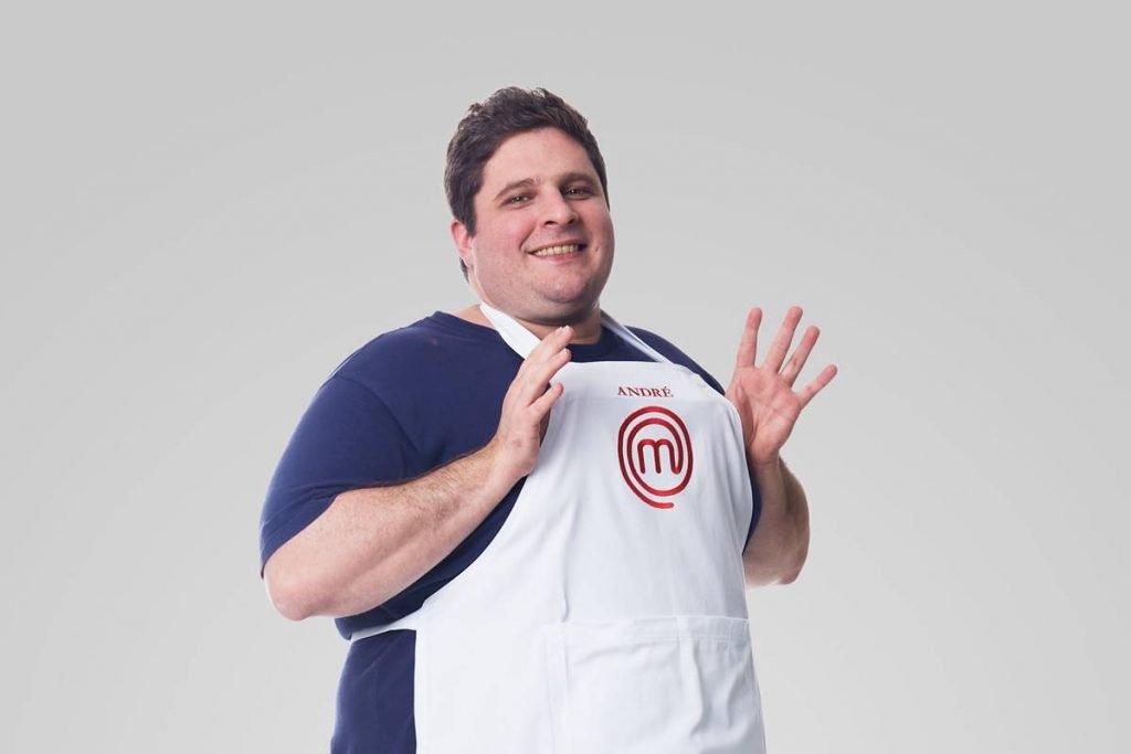Homem posa com avental do masterchef e sorri