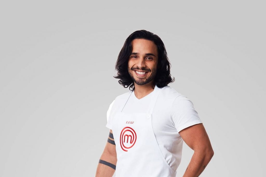 Homem posa com avental do masterchef e sorri