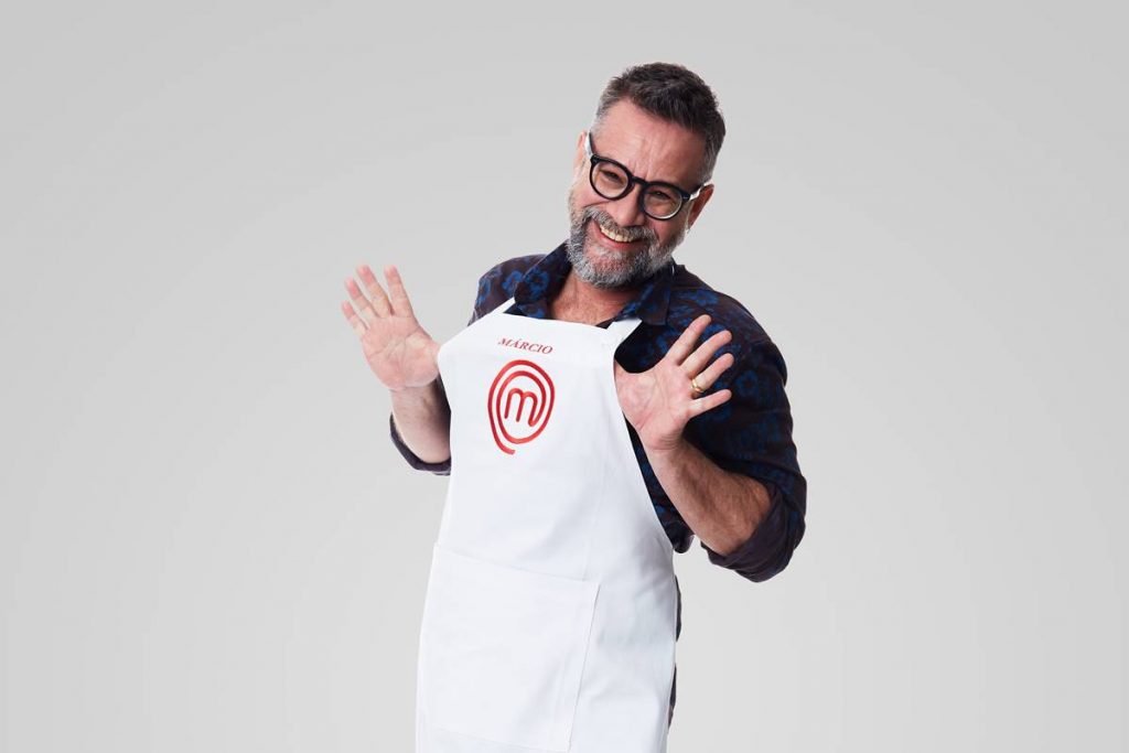 Homem posa com avental do masterchef e sorri