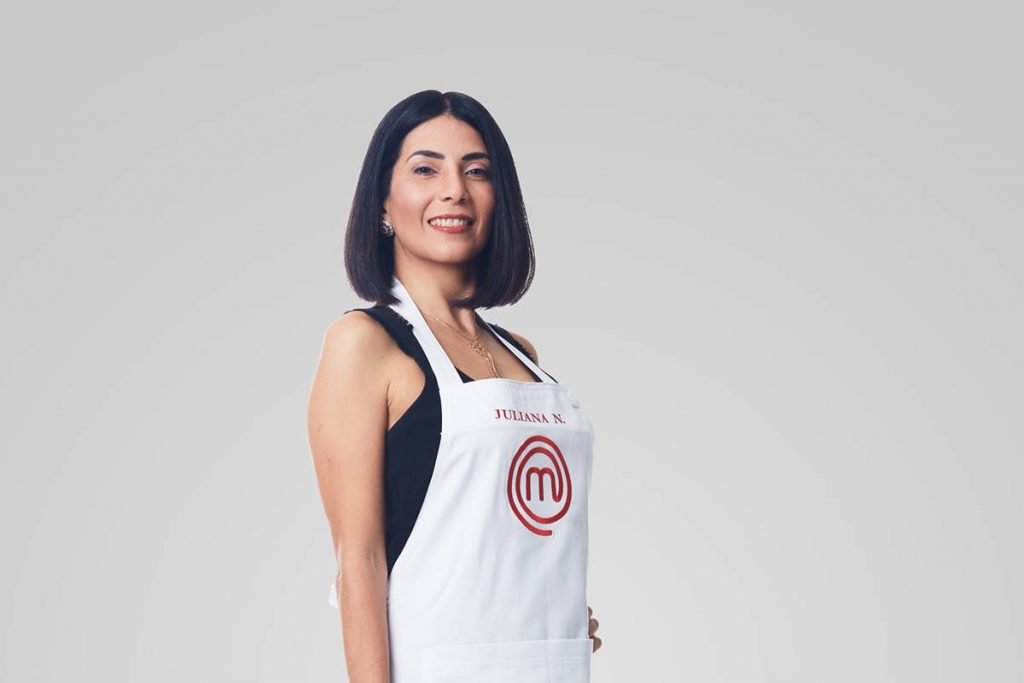 Mulher posa de avental do masterchef e sorri