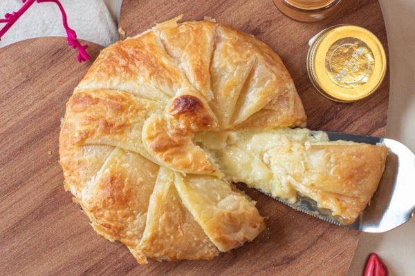 Brie envolto em massa folhada em cima de tábua de madeira