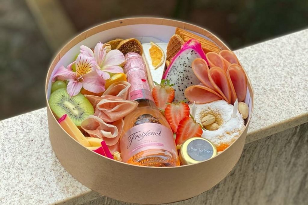 Caixa com frios, frutas, charcutaria e vinho