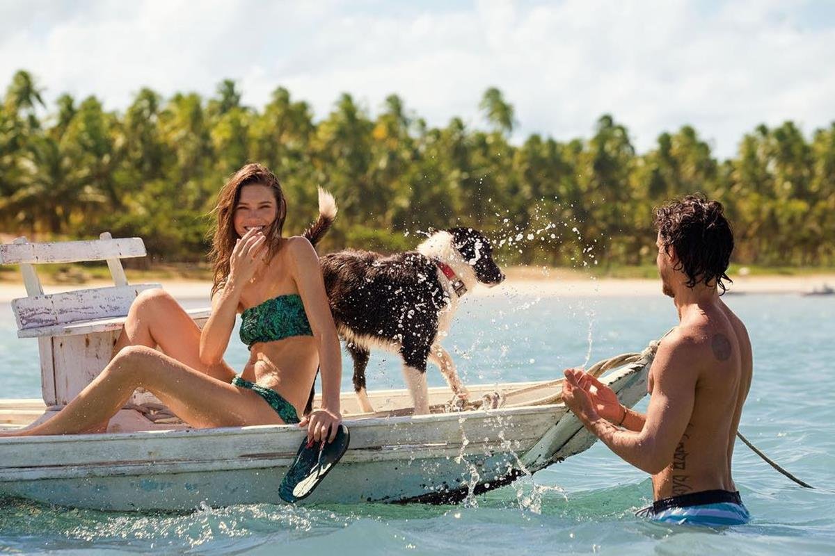 Casal em barco com cachorro, para campanha da Havaianas