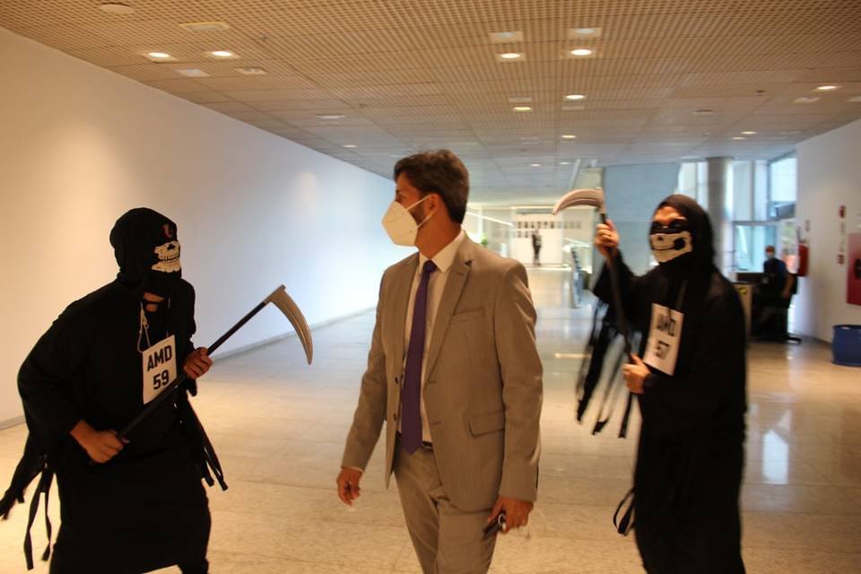 Na volta ao trabalho presencial, deputados são recebidos por atores vestidos de morte