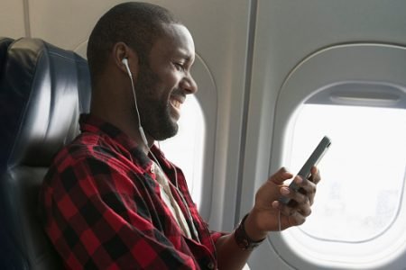 homem rindo para o celular em avião