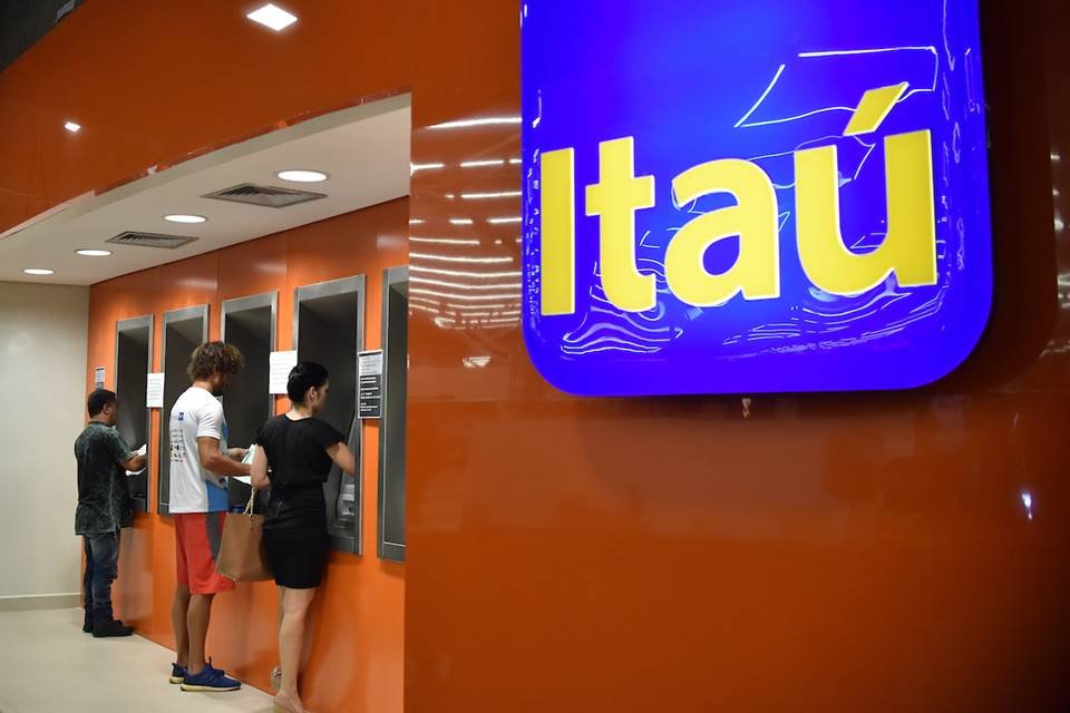 Imagem colorida mostra agência do Itaú e clientes em caixa eletrônico - Metrópoles