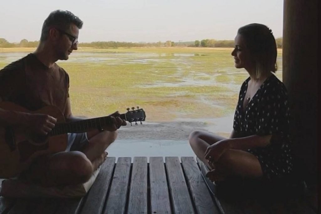 Sandy e Lucas Lima sentados em deck de madeira em foto contra a luz - metrópoles