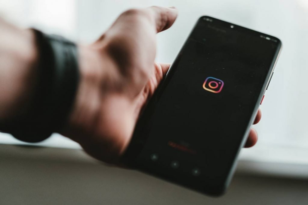 Mão segurando celular com logo doInstagram