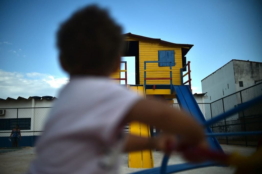 Criança de costas e parquinho ao fundo