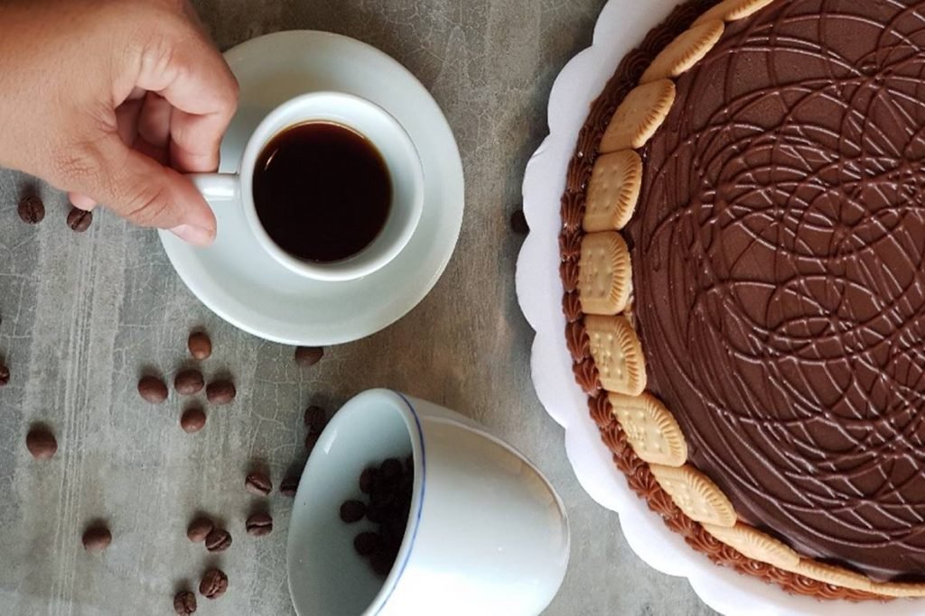 Xícara branca com café e torta ao lado