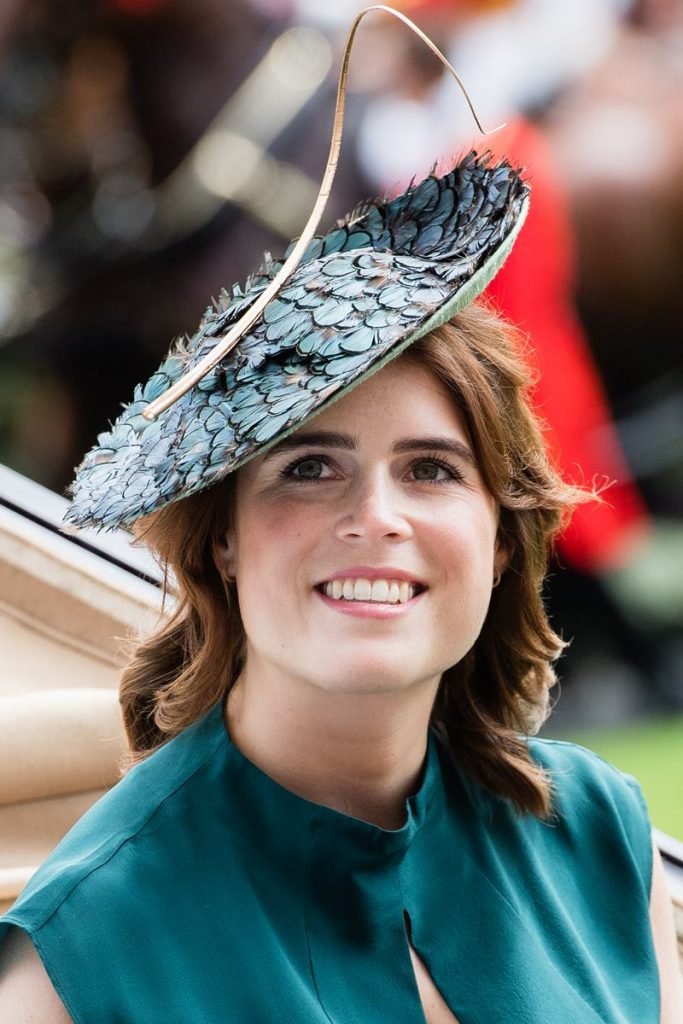 Na fotografia colorida, Princesa Eugenie aparece sorrindo para cima em evento