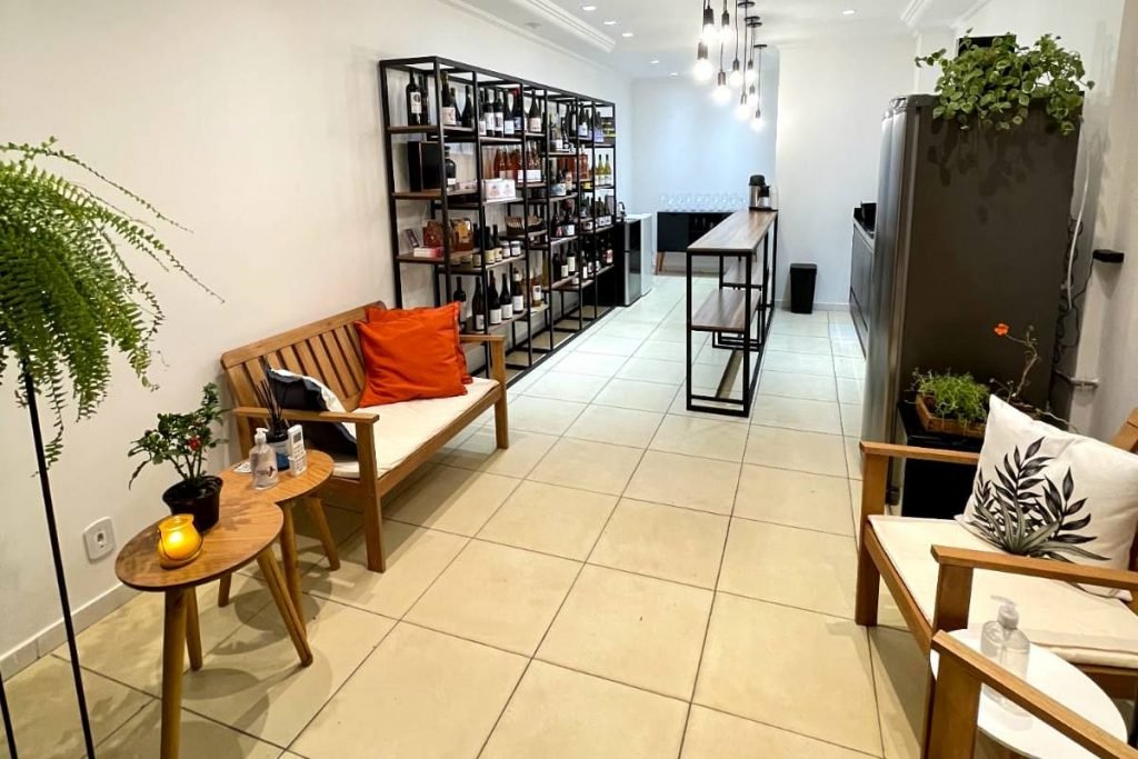espaço de loja com estante de vinhos e poltronas