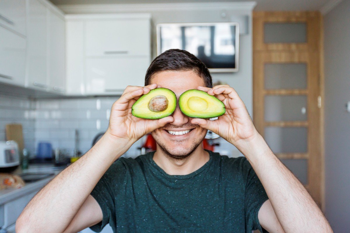 homem sorrindo segurando abacates rosto