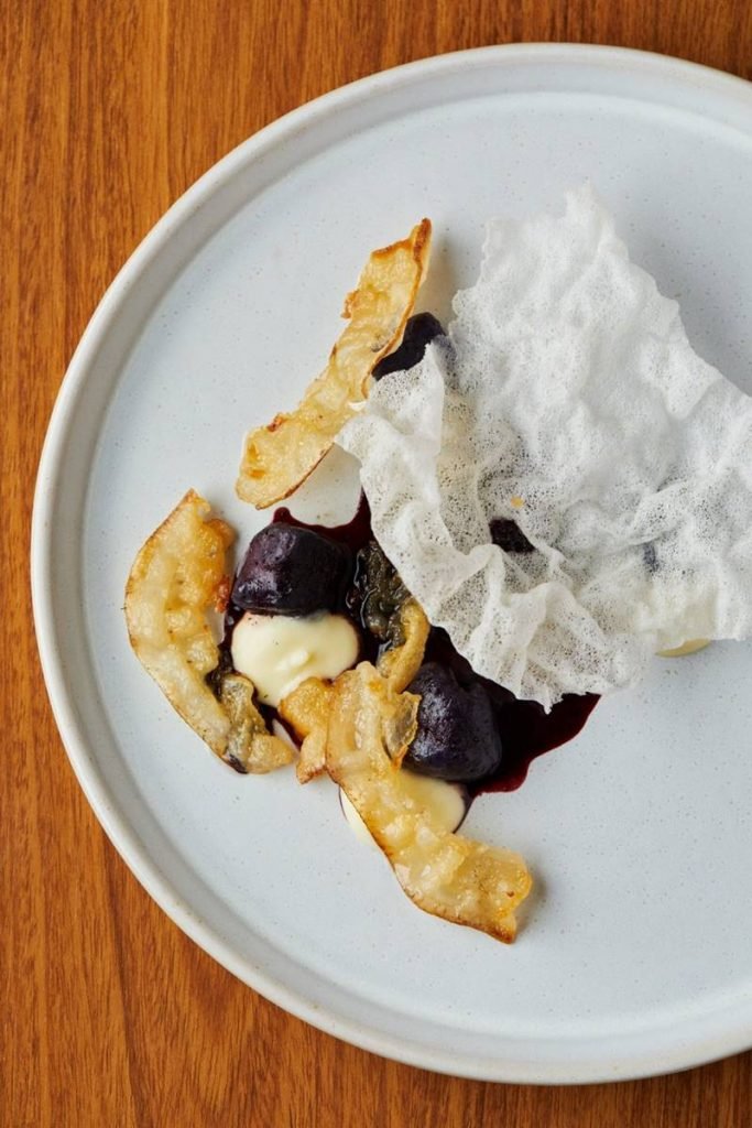 Nhoque de batata roxa com molho de açaí e creme de queijo e o lardo, gordura das costas do porco maturada por um ano