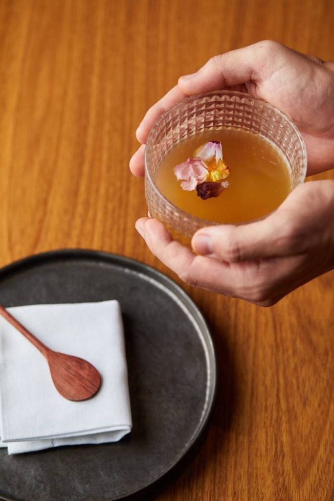 Chá de porco chega à mesa com um caldo feito de legumes, carne e osso de porco com pétalas de flores do Cerrado flutuando na superfície