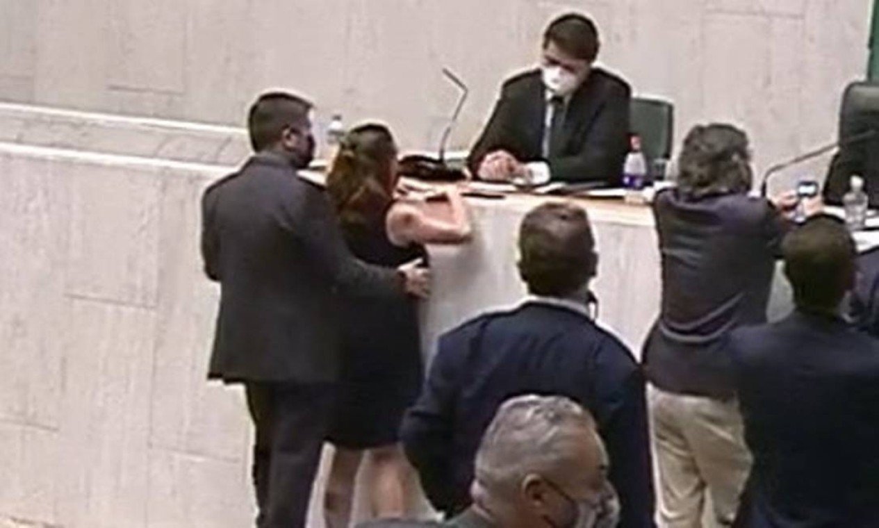 Imagem colorida mostra Fernando Cury, de terno preto, abraçando a deputada Isa Penna, de vestido preto, pelas costas e posiciona sua mão direita sobre o seio direito dela. os dois estão de costas, em pé - Metrópoles