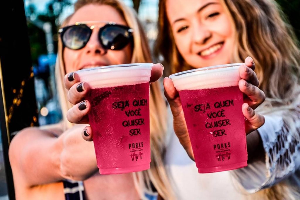 duas mulheres segurando copo com chope rosa dentro