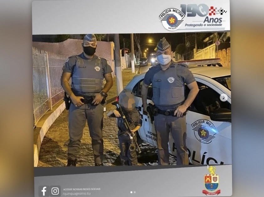 Criança fardada com uniforme da PM de São Paulo e segurando fuzil