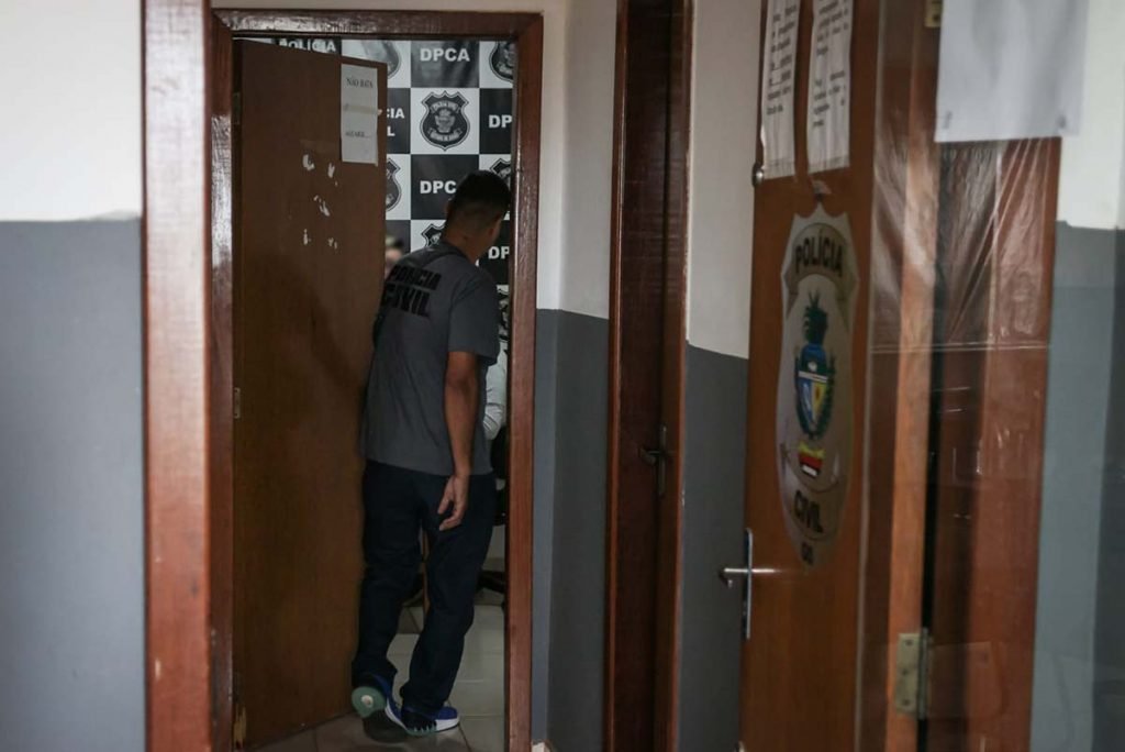 Duas portas amadeiradas. Uma com símbolo da PCGO e outra com um homem de camisa cinza entrando em uma das salas