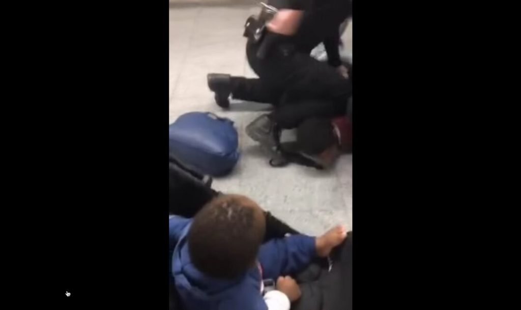 Dois seguranças dão mata-leão em homem negro enquanto bebê que estava com ele assiste a cena
