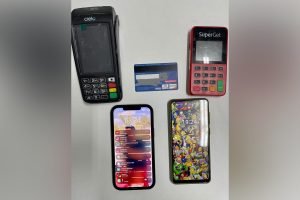 duas máquinas de cartão de crédito, dois celulares e um cartão de crédito