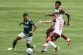 O atacante Dudu, do Palmeiras, corre com a bola enquanto é observado por dois jogadores do Flamengo