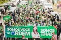 Pessoas na rua segurando cartaz grande