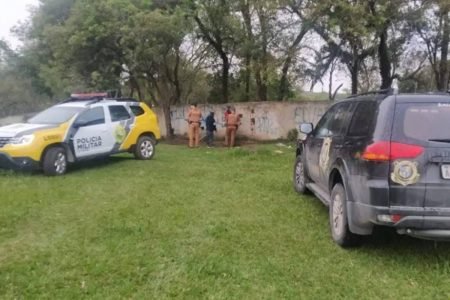 Carros da polícia e investigadores em local onde corpo foi achado