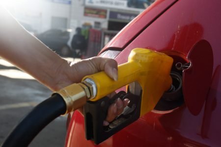 Frentista de posto de gasolina abastece carro vermelho com bomba amarela em posto - Metrópoles