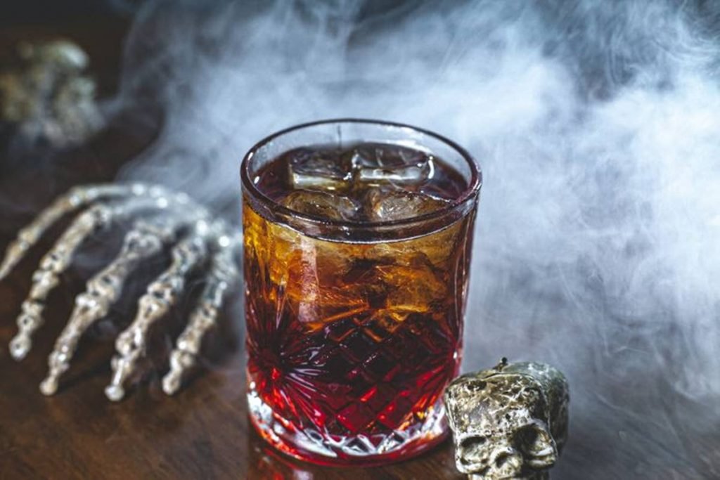 copo de drinque em meio a fumaça e decoração de dia das bruxas