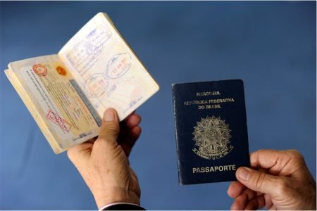 Imagem colorida mostra mão segurando passaportes - Metrópoles