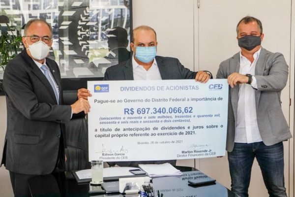 Três homens seguram cheque gigante