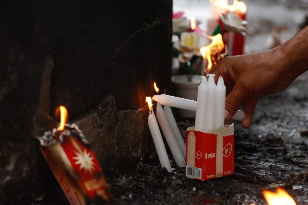 Familiar acende velas em sepultura de ente querido em Goiânia, Goiás
