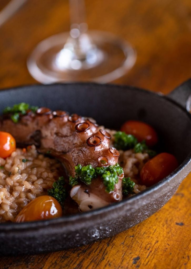 Tentáculo de polvo servido com arroz do próprio, açafrão espanhol e ervas