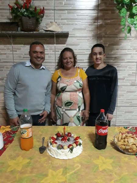 homem, mulher e adolescente em frente a bolo de aniversário