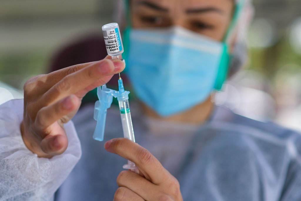 Enfermeira colocando vacinas em seringa